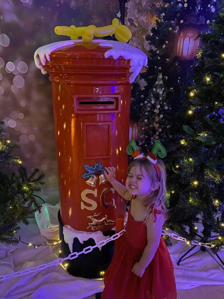 Flo laughing beside a Christmas postbox