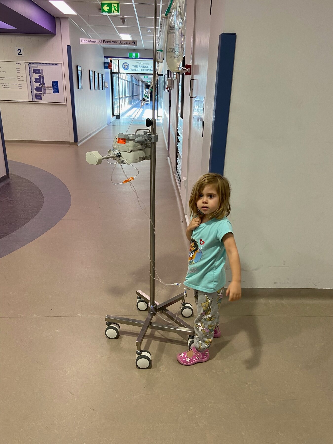 Flo walking through the hospital beside her IV pole